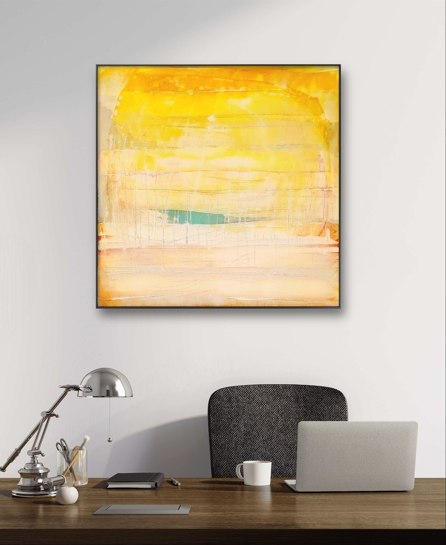 An einer weißen Wand steht ein moderner Büroschreibtisch mit Stuhl, Laptop, Lampe und Tasse, darüber hängt Conny Wachsmanns Bilderset „Farbflächen“ – ein markantes abstraktes Kunstwerk in Gelb, Orange und Beige mit schwarzem Rahmen.