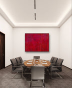 Ein moderner Konferenzraum mit einem runden Holztisch, acht grauen Stühlen, Wasserflaschen, Gläsern, Notizblöcken und Conny Wachsmanns Bilderset „Stärke“, einem abstrakten Kunstwerk in Rottönen auf einer weißen Wand für individuelle Gestaltung.