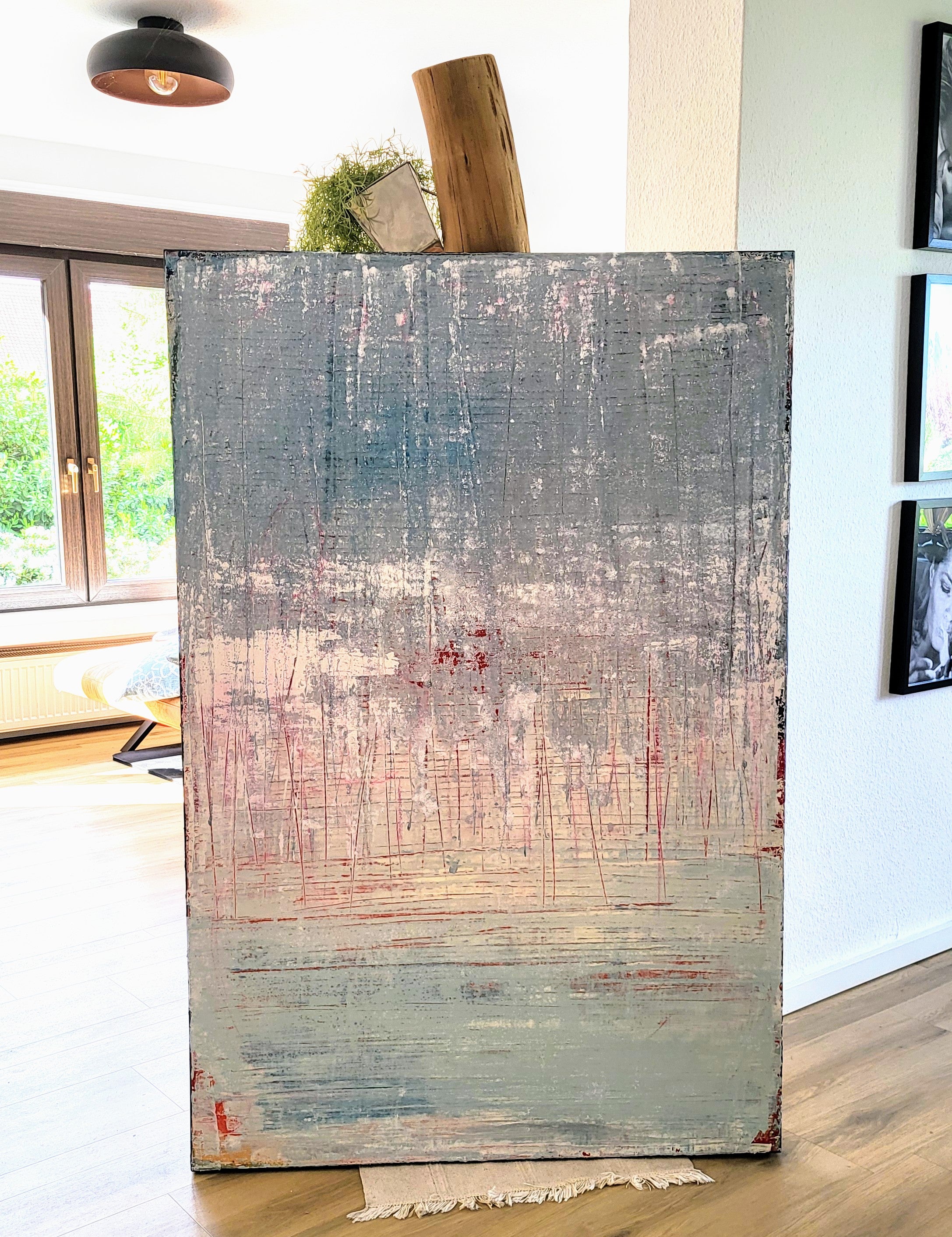 Vorschiedene Weiten von Conny Wachsmann, Künstlerin, ist ein großes Kratztechnik-Kunstwerk mit strukturierten blauen, grauen, weißen und roten Schichten. Es hebt sich von einer weißen Wand in einem hellen Raum ab - ideal für jede artvergnuegen galerie.