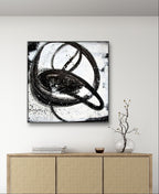 Ein minimalistisches Zimmer mit einem Sideboard aus hellem Holz, einer Glasvase mit kahlen Zweigen, einer kleinen Schale und "Nightswimming" von Conny Wachsmann, Künstlerin, einem großen abstrakten Gemälde mit kreisförmigen Formen, das an der weißen Wand darüber hängt.