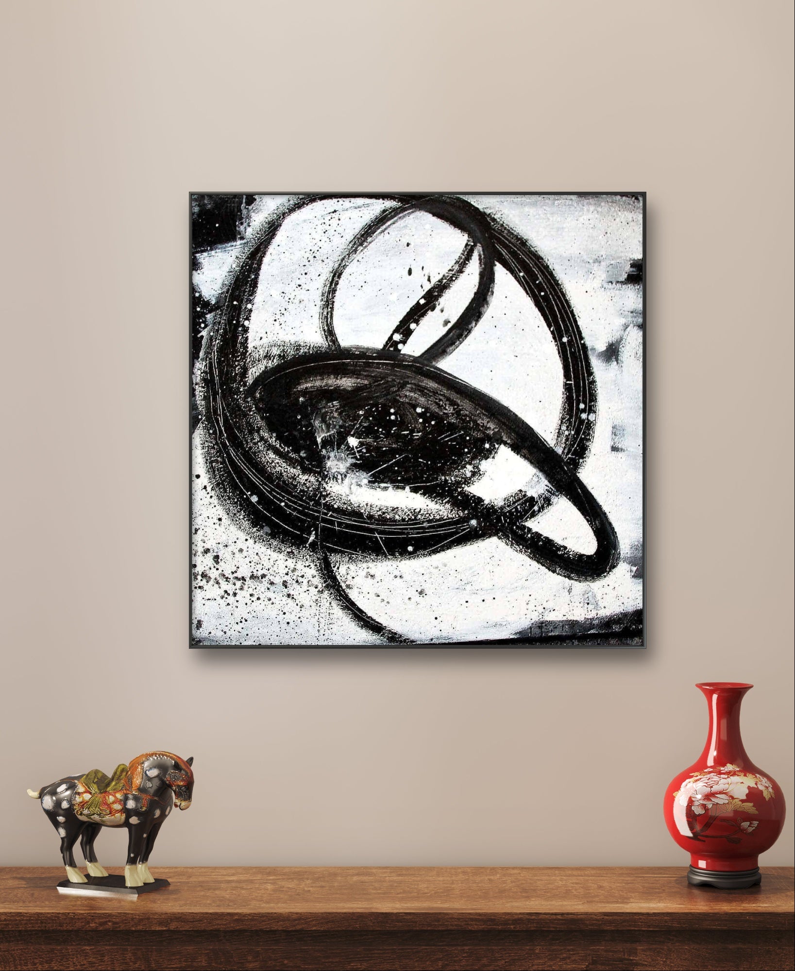 Das Kunstwerk "Nightswimming" von Conny Wachsmann, Künstlerin, mit kühnen, kreisförmigen Pinselstrichen in Schwarz und Weiß, hängt über einem Holzregal mit einer Pferdefigur und einer roten Vase und bringt einen raffinierten Stil in jeden Raum.