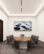 Ein moderner Konferenzraum ist mit einem ovalen Holztisch, acht grauen Stühlen, Wasserflaschen, Gläsern, Notizblöcken und Stiften ausgestattet. An der Wand hängt das Bilderset „S/W Moderne“ von Conny Wachsmann. Deckenleuchten erhellen den zeitgenössischen Raum.