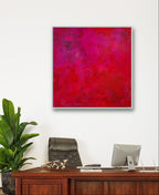 Ein modernes Büro mit Holzschreibtisch, Computer und Stuhl. Über dem Schreibtisch hängt das Bilderset „Stärke“ von Conny Wachsmann, dessen leuchtende Rottöne für eine individuelle Note sorgen. Eine Grünpflanze bringt Frische in den Raum.