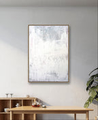 Ein minimalistisches Zimmer mit einer hellen Holzanrichte, einem Teekannenset und einer Pflanze. Darüber hängt "Stiller Spaziergang" von Conny Wachsmann, Künstlerin - abstrakte Kunst in sanftem Weiß und hellem Grau, die Ruhe in den ruhigen Raum bringt.