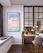 Modernes Home-Office mit Holzschreibtisch, Lampe, Büchern und farbenfroher Dekoration. Über der Fensterbank hängt "Vorschiedene Weiten" von Conny Wachsmann, dessen blau-weiße Töne sich in der Glaswand der artvergnuegen galerie spiegeln.