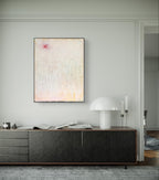 Minimalistisches Wohnzimmer mit niedrigem, dunklem Sideboard, „Gedankenregen“ von Conny Wachsmann, Künstlerin in sanften Pastelltönen an der Wand, dazu eine moderne weiße Tischleuchte, Kerzen, Bücher und Deko-Objekte übersichtlich arrangiert.