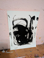 Zeichnungen & Reduktion IV" von Conny Wachsmann, Künstlerin: Eine minimalistische Originalzeichnung in Schwarz-Weiß mit abstrakten Pinselstrichen, angelehnt an eine strukturierte rosa Wand auf einem holzfarbenen Untergrund.