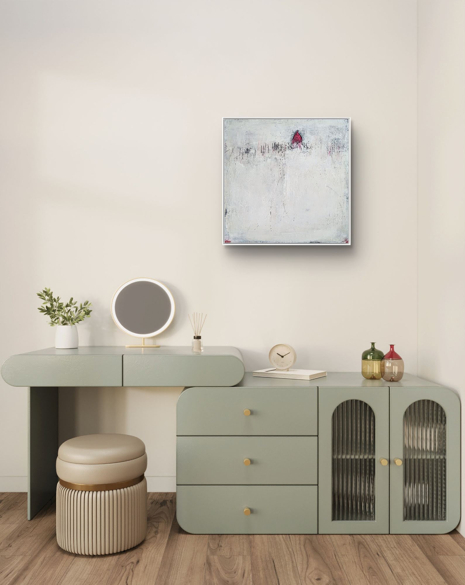 Ein minimalistischer Schminktisch mit einem salbeigrünen Schreibtisch, einem runden Spiegel, einem Hocker und einer kleinen Pflanze. Darüber hängt „Stille Spur“ von Conny Wachsmann – ein originales strukturiertes weiß-rotes Gemälde – an der beigefarbenen Wand. Holzboden rundet das moderne Dekor ab.