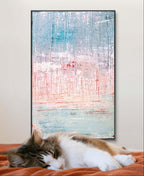 Eine gestromte, weiße Katze schläft auf einer orangefarbenen Decke vor einer Wand, die mit "Vorschiedene Weiten" der Künstlerin Conny Wachsmann mit blauen, rosa und weißen Pinselstrichen geschmückt ist.