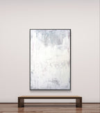 Das Kunstwerk "Stiller Spaziergang" von Conny Wachsmann, Künstlerin, in sanften Weiß-, Grau- und hellen Rosatönen hängt über einer Holzbank in einem minimalistischen Raum und schafft eine Atmosphäre von Ruhe und Entspannung.