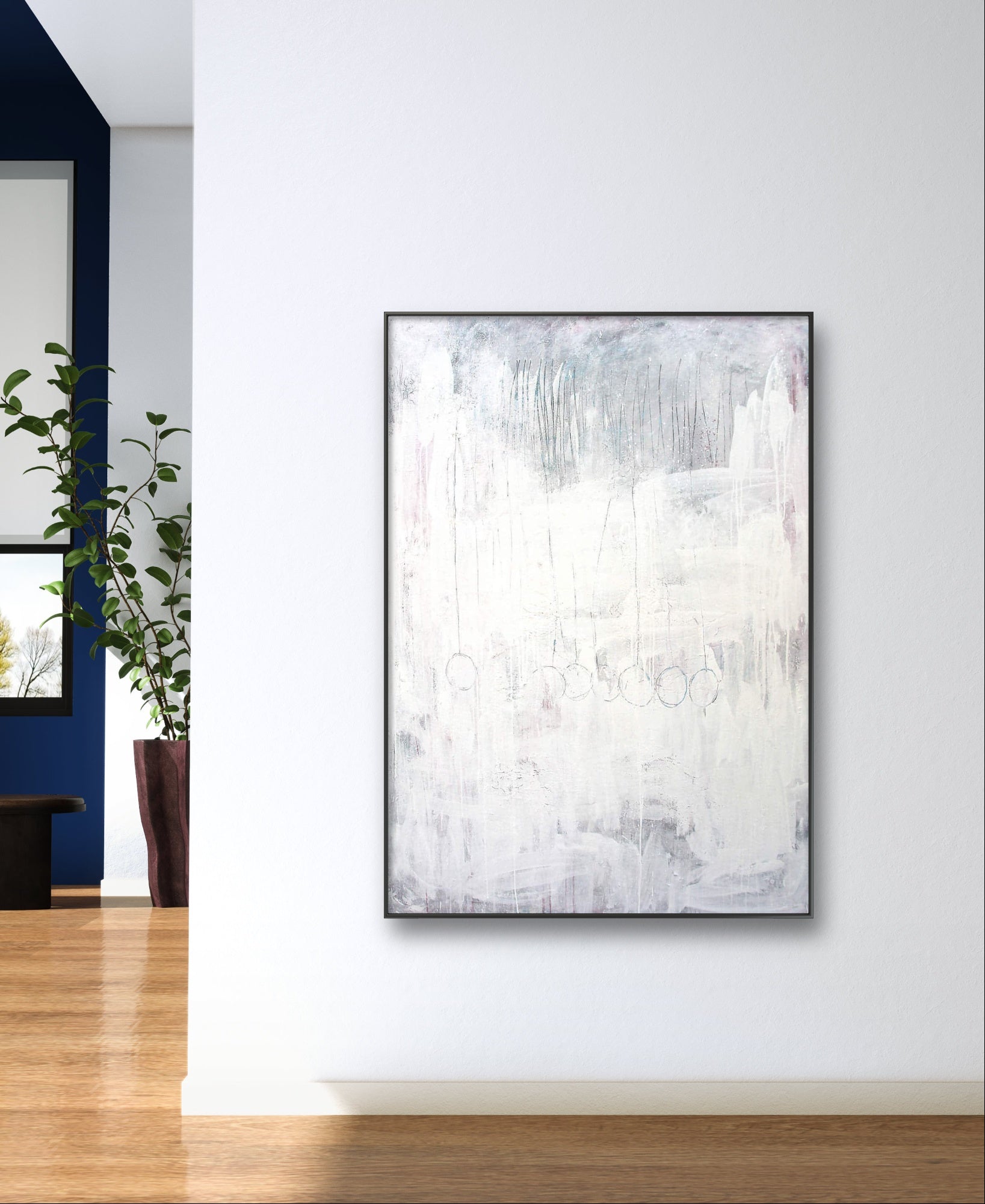 Das Bild "Stiller Spaziergang" von Conny Wachsmann, Künstlerin, in Weiß- und Grautönen hängt an einer weißen Wand mit Holzboden und grüner Pflanze - und verleiht dem Raum Ruhe sowie Entspannung.