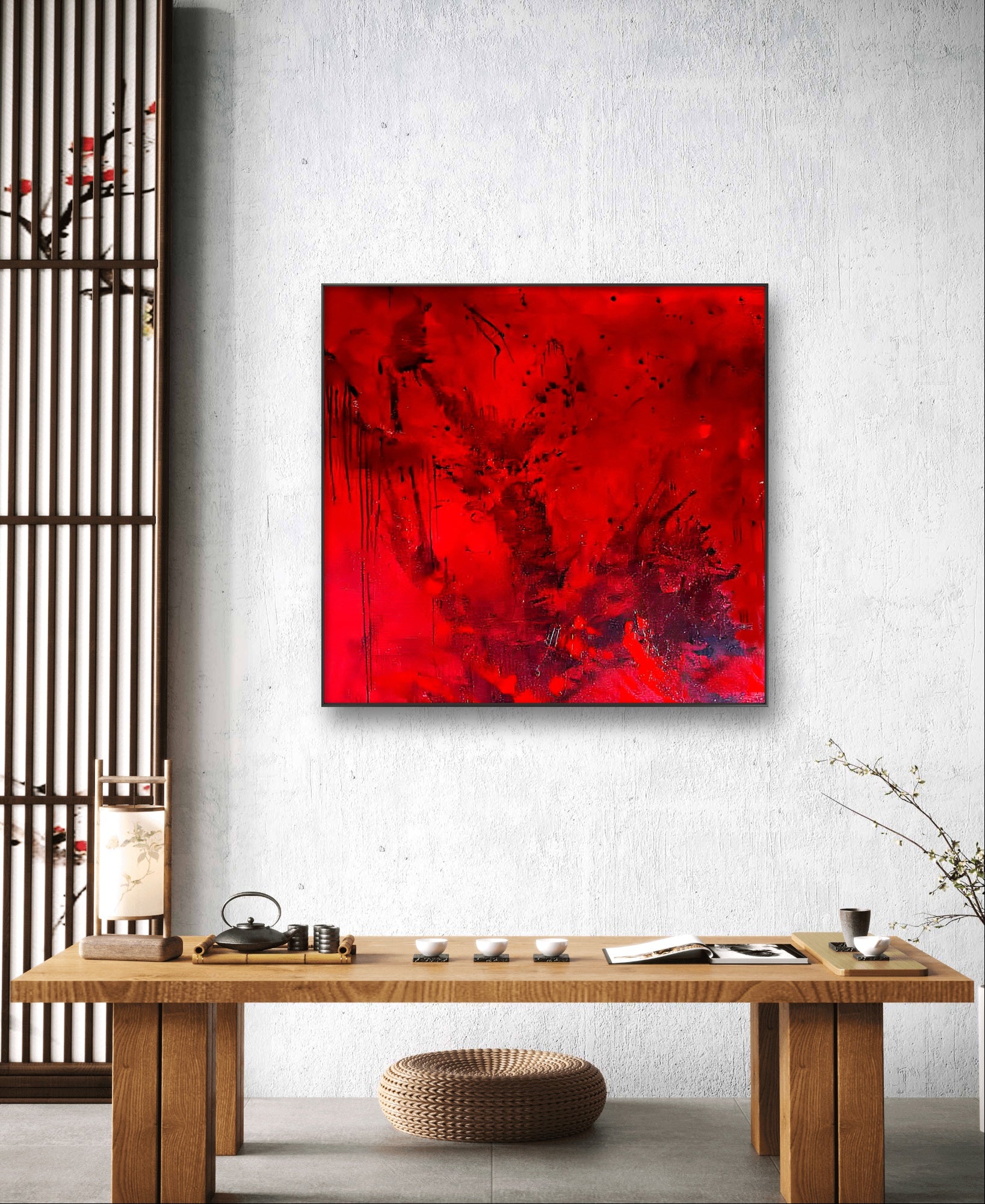 Ein minimalistischer Raum mit einem niedrigen Holztisch für den Tee, einem kleinen runden Kissen und "Butterfly", einem kühnen abstrakten roten Gemälde von Conny Wachsmann an einer weißen Wand. Ein Shoji-Schirm und eine Vase mit spärlichen Zweigen vervollständigen den ruhigen Raum.