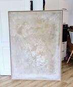 „Spurensuche“, ein abstraktes Kunstwerk von Conny Wachsmann, zeigt sanfte Weiß-, Creme- und Hellbeigetöne. Präsentiert mit einem stilvollen Schattenfugenrahmen in einem modernen Raum mit Holzböden und weißen Möbeln, verleiht es raffinierte Eleganz.