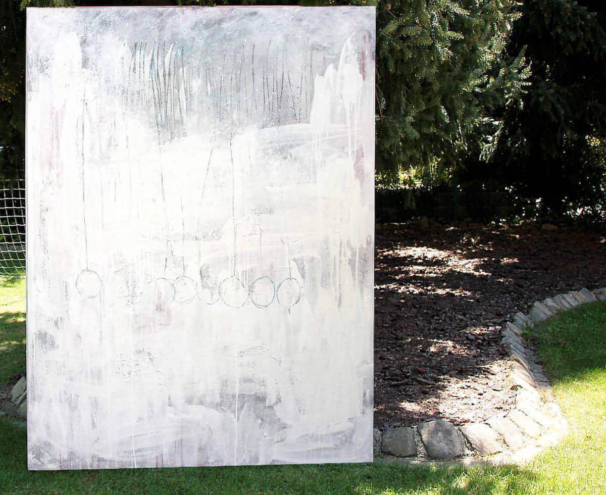 Stiller Spaziergang" von Conny Wachsmann, Künstlerin: Ein großes abstraktes Kunstwerk mit weißen, grauen und feinen Kreisen lehnt im Freien am Baum und strahlt Ruhe sowie Entspannung durch Licht- und Schattenspiele aus.