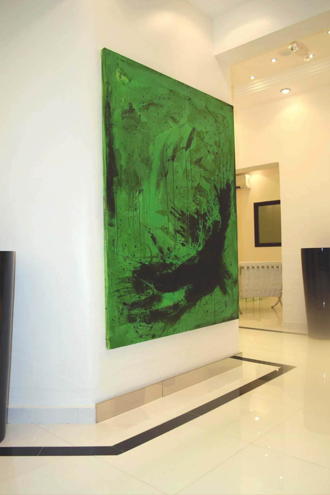 Das große abstrakte Gemälde "Schmetterling" der Künstlerin Conny Wachsmann in den Farben Grün und Schwarz hängt an einer weißen Wand in einem modernen minimalistischen Raum mit weißem Hochglanzboden und Einbaubeleuchtung.