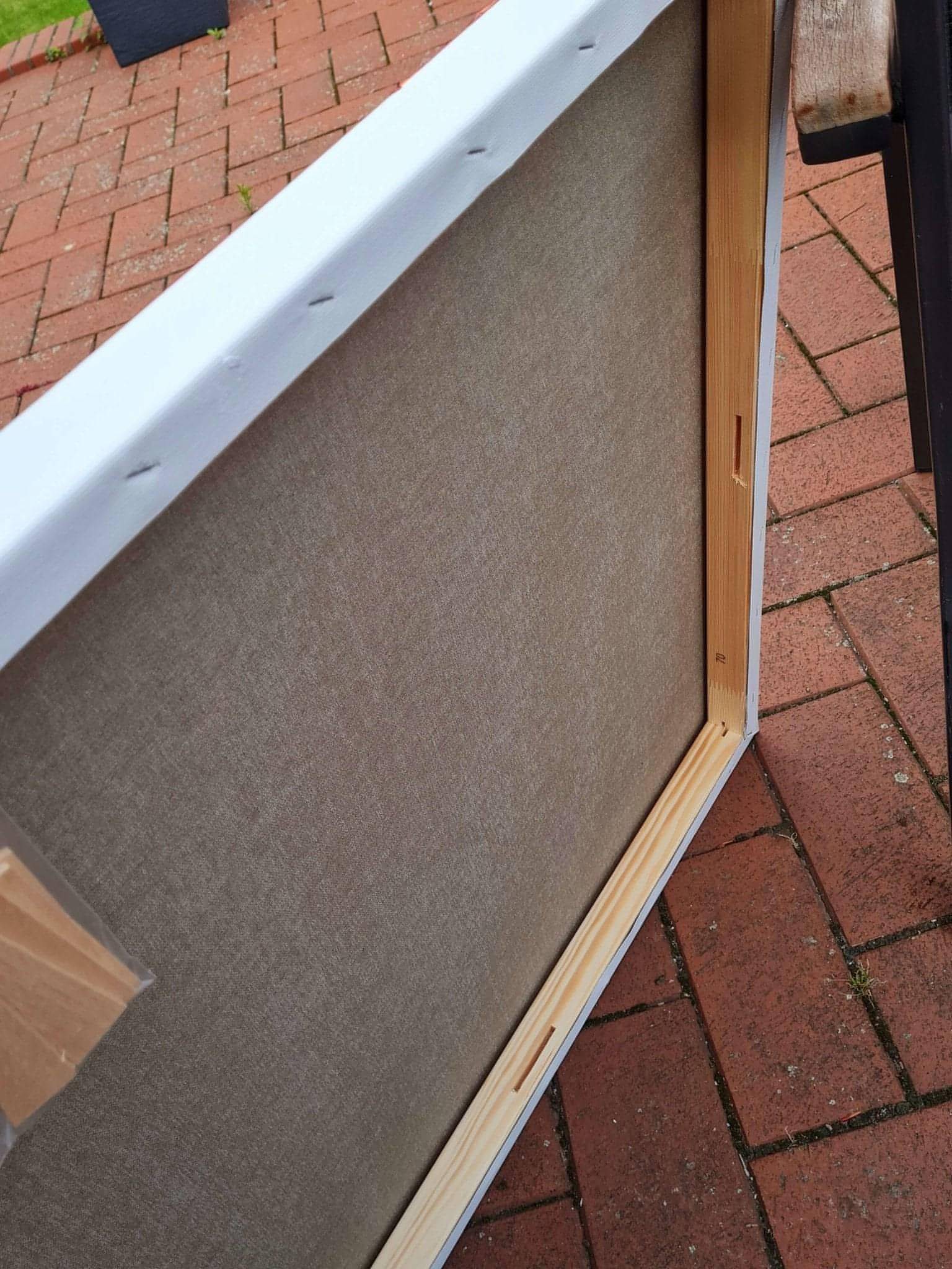 Eine Nahaufnahme der Rückseite von Conny Wachsmanns "Butterfly"-Leinwand zeigt den Holzrahmen und ein Stück braunes Klebeband an einer Ecke, das auf einer Backsteinterrasse liegt. Perfekt für Kunst nach Maß oder großformatige Bilder.