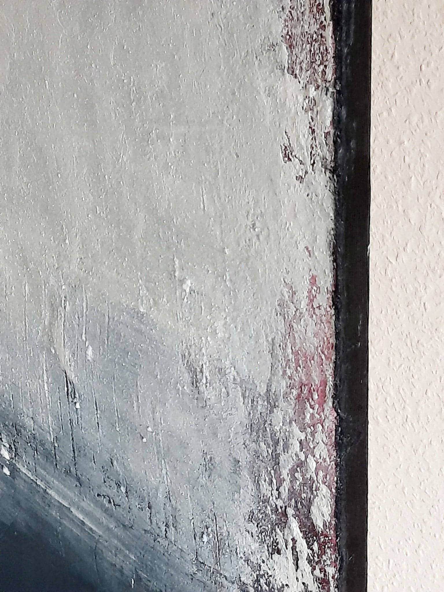 Nahaufnahme von "Ein Ausweg" von Conny Wachsmann: Strukturen aus Weiß, Grau und einem Hauch Rot, raue Oberfläche und Pinselstriche nahe dem schwarzen Rahmen - ein echtes abstraktes Kunstwerk.
