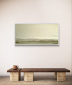 Ein minimalistischer Raum mit einer niedrigen Holzbank und einer Teekanne aus Keramik, in dem "Zwischen Sommer und Herbst II" von Conny Wachsmann - eine abstrakte Landschaft in Beige und Grün - an einer cremefarbenen Strukturwand hängt.