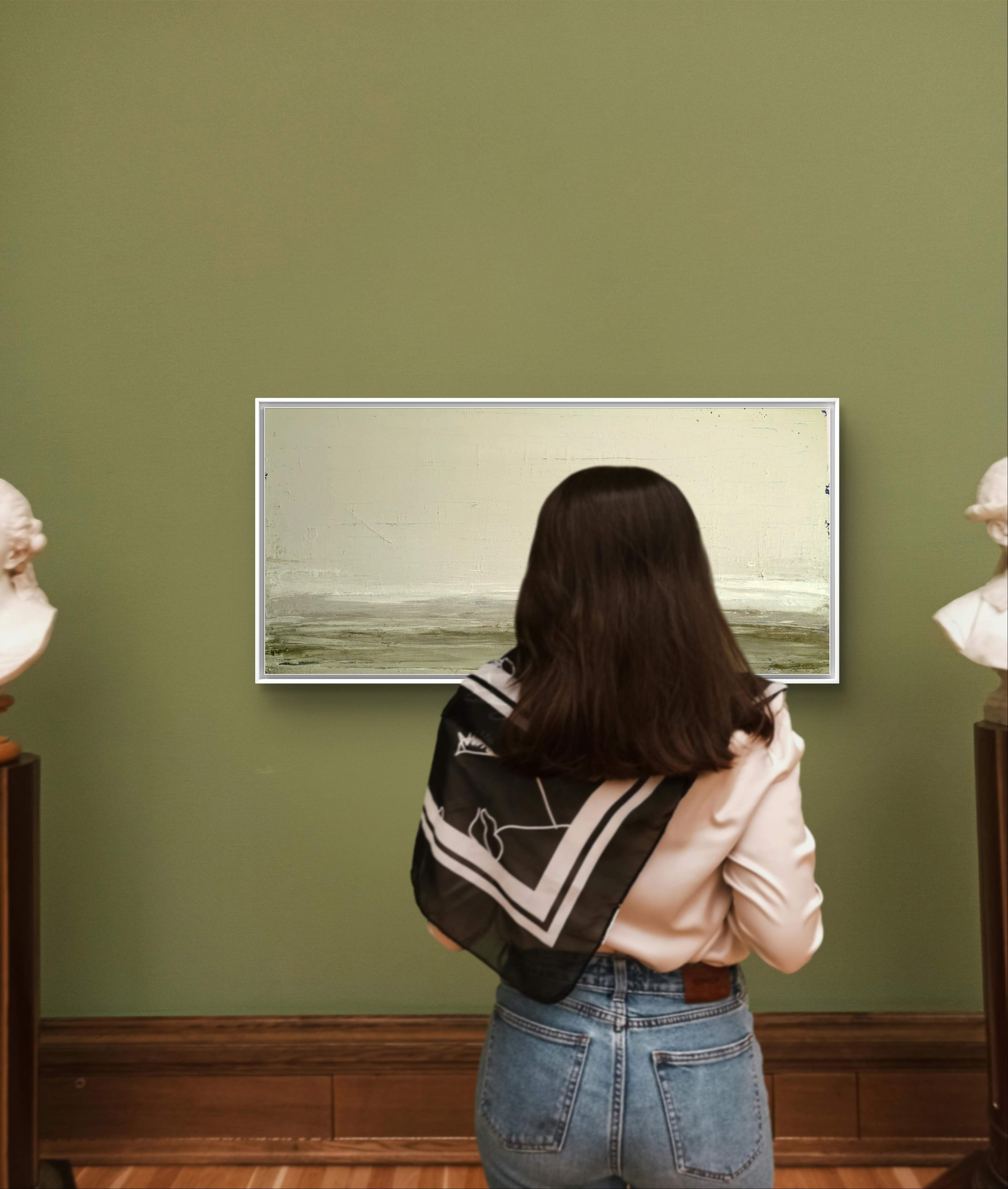 Eine Frau mit langen dunklen Haaren, bekleidet mit weißem Hemd, Jeans und schwarzem Schal, steht vor "Zwischen Sommer und Herbst II" der Künstlerin Conny Wachsmann an einer grünen Galeriewand, flankiert von zwei weißen Büsten.