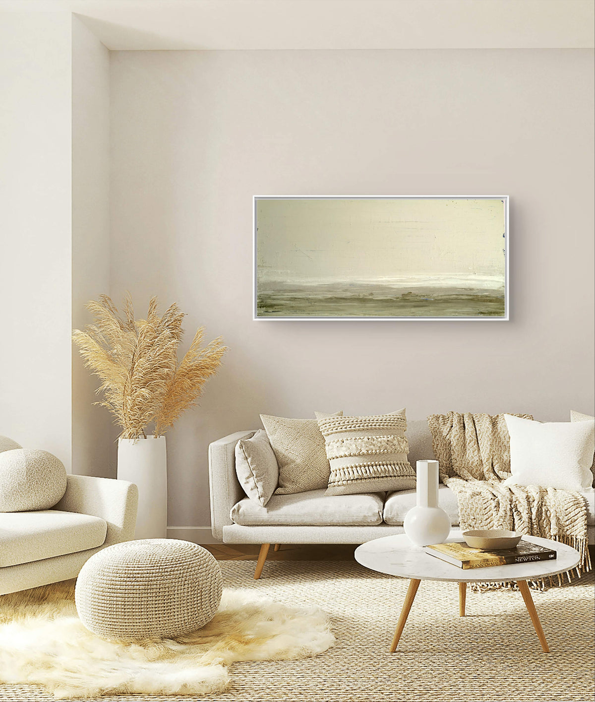 Ein gemütliches, in neutralen Tönen gehaltenes Wohnzimmer mit einem beigen Sofa, strukturierten Kissen und Überwürfen, einem runden Hocker, Pampasgras in einer Vase, einem weißen Couchtisch und "Zwischen Sommer und Herbst II" von Conny Wachsmann über dem Sofa für eine einzigartige künstlerische Note.