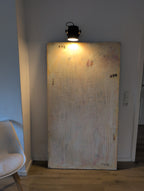 Das Bild "Eichhörnchentanz" von Conny Wachsmann, Künstlerin, in dezenten Farben lehnt an einer weißen Wand unter Spotlicht. Links steht ein weißer Stuhl, rechts ein Lichtschalter - stilvolle Wanddekoration für moderne Räume.