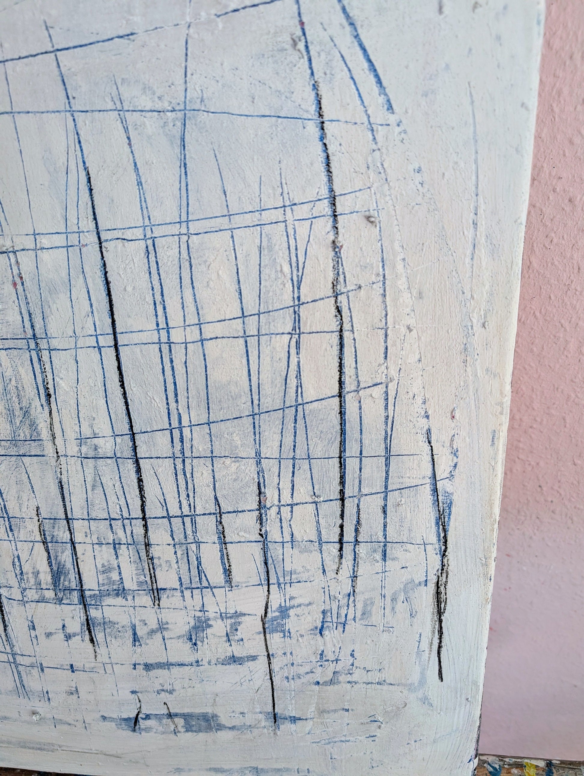 Eine Nahaufnahme von „Feldlinien“ von Conny Wachsmann, einem abstrakten Acrylgemälde auf Leinwand mit feinen blauen und schwarzen Linien über strukturiertem Weiß, vor einer rosa Wand, das seine einzigartige Tiefe und Struktur zur Schau stellt.